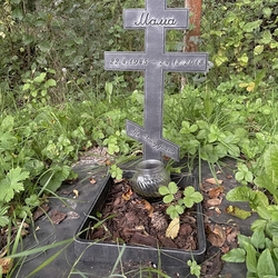 Geschmiedetes Urnenmonument mit Kreuz und Inschrift im Garten