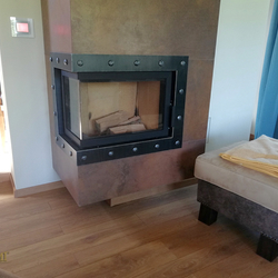 Schmiedeeiserner Rahmen mit historischem Motiv am Kamin im Wohnzimmer Schmiedeeiserner Rahmen mit historischem Motiv am Kamin im Wohnzimmer